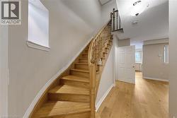 Curved hardwood staircase with wood balusters, hardwood flooring, and white trim details - 