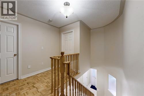 Hardwood flooring with a parquet pattern, wooden staircase railing, multiple paneled doors, and a ceiling-mounted light fixture - 21 Eastview Gate Unit# 36, Brampton, ON 
