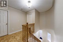 Hardwood flooring with a parquet pattern, wooden staircase railing, multiple paneled doors, and a ceiling-mounted light fixture - 
