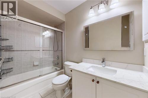 Tub and shower combination with sliding glass doors, vanity with integrated sink and chrome faucet, and decorative framed mirror with sconce lighting - 21 Eastview Gate Unit# 36, Brampton, ON 