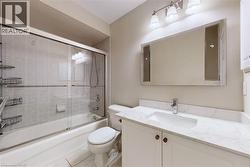 Tub and shower combination with sliding glass doors, vanity with integrated sink and chrome faucet, and decorative framed mirror with sconce lighting - 