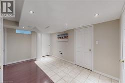 Recessed lighting illuminates neutral-toned walls and a combination of tile and wood-finish flooring - 