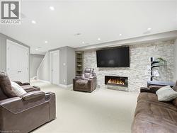 Entertainment room featuring a stone accent wall, linear fireplace, recessed lighting, and built-in shelving - 