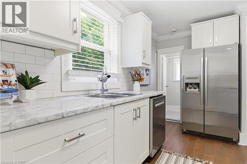White shaker cabinetry, marble-finish countertops, stainless steel appliances, subway tile backsplash, and wood-finish flooring - 87 Strathcona Avenue, Brantford, ON 