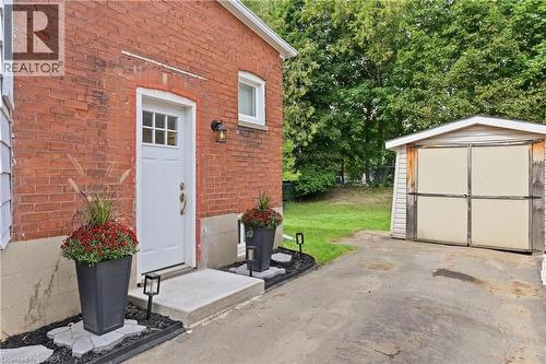 Brick exterior with white trim, concrete entry pad, and exterior lighting fixture - 87 Strathcona Avenue, Brantford, ON 