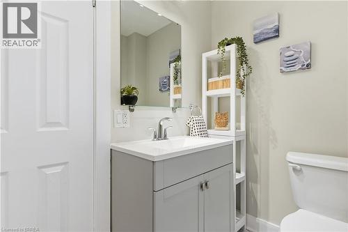 White paneled door, gray vanity with double-door cabinetry, integrated white sink, chrome faucet, and rectangular mirror - 87 Strathcona Avenue, Brantford, ON 