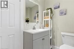 White paneled door, gray vanity with double-door cabinetry, integrated white sink, chrome faucet, and rectangular mirror - 