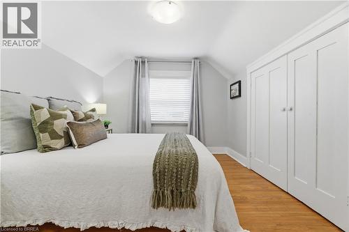 Hardwood flooring, painted paneled double closet doors, window with blinds and drapes, and a ceiling-mounted light fixture - 87 Strathcona Avenue, Brantford, ON 