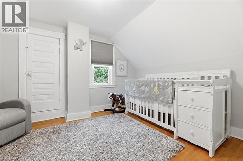 Wood-finish flooring with white trim, window with privacy blind, and a white paneled door - 87 Strathcona Avenue, Brantford, ON 