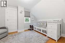Wood-finish flooring with white trim, window with privacy blind, and a white paneled door - 