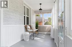 Enclosed porch with wide plank flooring, beadboard wainscoting, and a hanging light fixture - 
