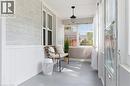 Enclosed porch with wide plank flooring, beadboard wainscoting, and a hanging light fixture - 87 Strathcona Avenue, Brantford, ON 