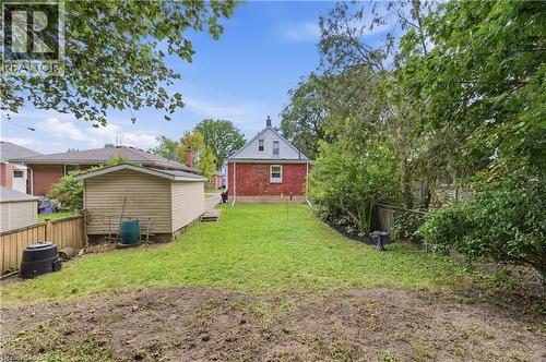 Expansive backyard featuring a manicured lawn, established landscaping, and a detached shed - 87 Strathcona Avenue, Brantford, ON 