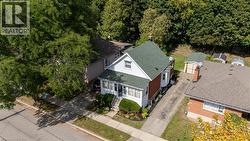 White siding exterior with brick accents, green shingle roof, and a mature tree canopy - 
