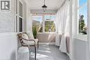 Enclosed porch featuring shiplap accent walls, wood-finish flooring, multiple windows, and a hanging light fixture - 87 Strathcona Avenue, Brantford, ON 
