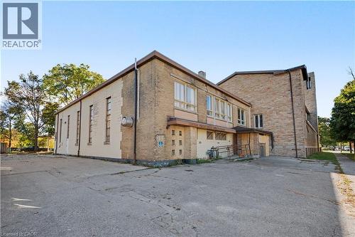 Brick exterior with multiple window configurations and a concrete parking area - 97 Wellington Street, Brantford, ON 