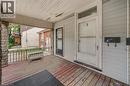 Covered front porch featuring wood-finish flooring, stone-clad columns, and wrought iron railing - 211 Wentworth Street N, Hamilton, ON 