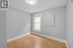 Wood-finish flooring, white trim, and a window with a white frame - 
