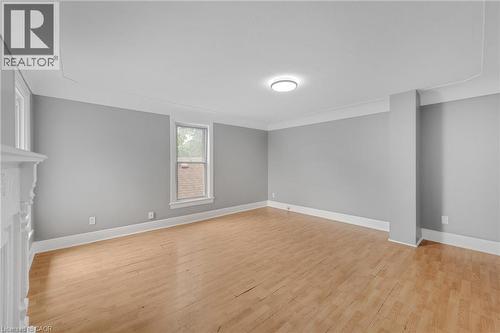 Light wood-finish flooring, neutral gray wall tones, crown molding, white trim, and an overhead light fixture - 211 Wentworth Street N, Hamilton, ON 
