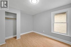 Recessed closet with a clothes rod, wood-finish flooring, single window, and a ceiling-mounted light fixture - 