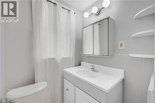 Vanity with an integrated sink and chrome faucet, medicine cabinet with mirrored doors, and wall-mounted spherical light fixture - 211 Wentworth Street N, Hamilton, ON 