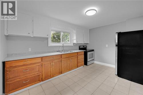 Kitchen featuring a dual basin stainless steel sink, tile flooring, wood cabinetry, and a built-in range - 211 Wentworth Street N, Hamilton, ON 