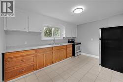 Kitchen featuring a dual basin stainless steel sink, tile flooring, wood cabinetry, and a built-in range - 