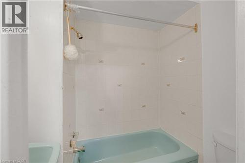 Bathroom featuring a bathtub with a shower and white tiled walls - 211 Wentworth Street N, Hamilton, ON 