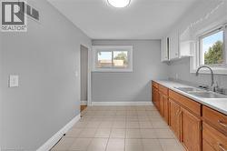 Kitchen featuring wood cabinetry, a dual basin stainless steel sink, a modern pull-down faucet, and tile flooring - 