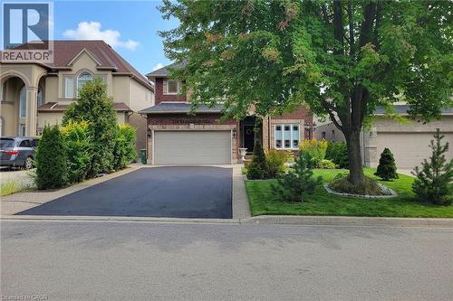 Brick facade with a double-car garage and asphalt driveway - 214 Cloverleaf Drive, Ancaster, ON 