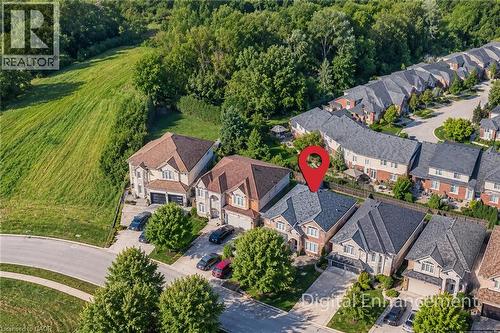 Brick facade residence with a gabled roof, attached garage, and paved driveway - 214 Cloverleaf Drive, Ancaster, ON 