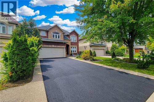 Brick and stone facade, arched entryway, attached two-car garage, paved driveway, and established landscaping - 214 Cloverleaf Drive, Ancaster, ON 