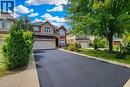 Brick and stone facade, arched entryway, attached two-car garage, paved driveway, and established landscaping - 214 Cloverleaf Drive, Ancaster, ON 