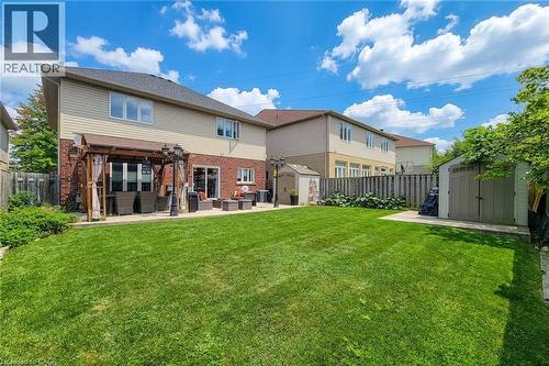 Expansive green lawn with a privacy fence, two garden sheds, and an outdoor patio featuring a pergola - 214 Cloverleaf Drive, Ancaster, ON 