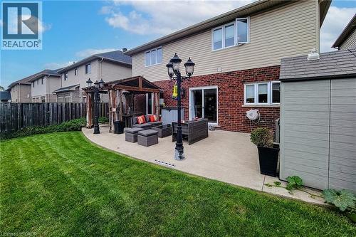 Expansive backyard featuring a manicured lawn, concrete patio, and a wood pergola - 214 Cloverleaf Drive, Ancaster, ON 