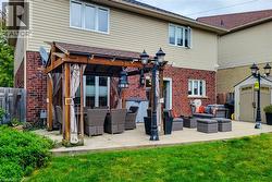 Expansive concrete patio featuring a wood pergola, brick exterior, and manicured lawn - 