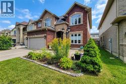 Brick and stone facade with arched windows, an integrated garage, and a landscaped front garden - 