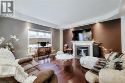 Tray ceiling with recessed lighting, wood-finish flooring, and a fireplace with a mantel - 