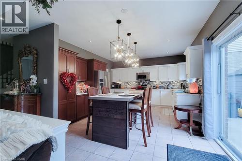 Kitchen featuring a large center island with seating, a mix of wood-tone and white cabinetry, a tile backsplash, recessed lighting, and a sliding glass door - 214 Cloverleaf Drive, Ancaster, ON 
