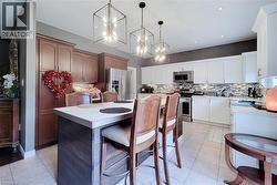 Kitchen featuring a multi-tone cabinetry design, central island with a light-toned countertop, stainless steel appliances, and a mosaic tile backsplash - 