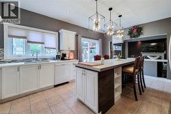 Kitchen featuring a center island with seating, white cabinetry, integrated dishwasher, and tile flooring - 