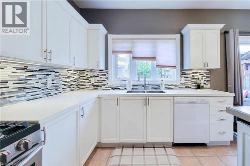 White cabinetry with polished hardware, light-toned countertops, and a mosaic tile backsplash - 214 Cloverleaf Drive, Ancaster, ON 