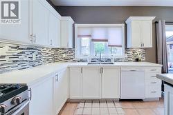 White cabinetry with polished hardware, light-toned countertops, and a mosaic tile backsplash - 