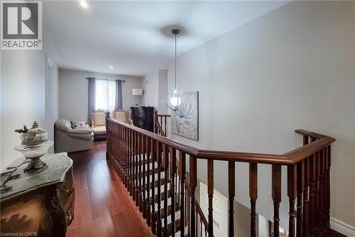 Hardwood flooring throughout, with a wood-spindle staircase railing, recessed lighting, and a modern pendant light fixture - 214 Cloverleaf Drive, Ancaster, ON 