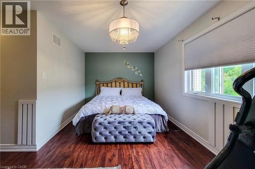Wood-finish flooring, single window with roller shade, accent wall, ceiling-mounted light fixture, and vertical wall paneling - 214 Cloverleaf Drive, Ancaster, ON 