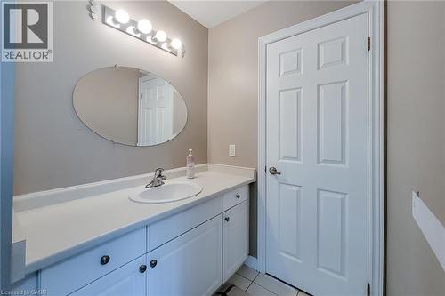 White vanity with integrated sink, chrome faucet, and oval mirror - 214 Cloverleaf Drive, Ancaster, ON 