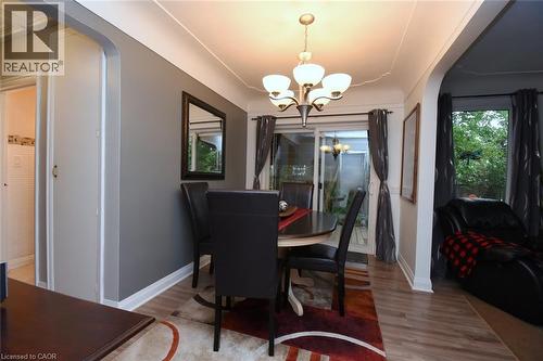 Wood-finish flooring, sliding glass door, overhead chandelier, arched doorway, and white trim - 154 Ewen Road, Hamilton, ON 