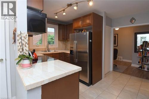 Kitchen featuring wood cabinetry, stainless steel appliances, a light-toned tile backsplash, and track lighting - 154 Ewen Road, Hamilton, ON 