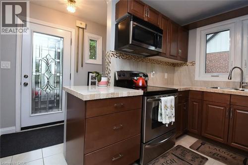 Kitchen featuring wood-finish cabinetry, stainless steel appliances, and a tile backsplash - 154 Ewen Road, Hamilton, ON 