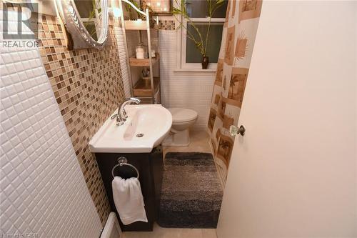 Vanity with an integrated white sink, mosaic tile wall, polished chrome faucet, and white square tile wall - 154 Ewen Road, Hamilton, ON 
